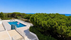 Una piscina con vistas al mar, rodeada de vegetación.