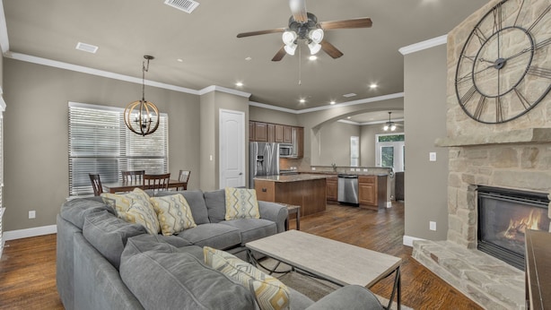 A spacious living room with a gray sectional sofa, a fireplace, and a kitchen in the background. - Townhome Located in the heart of Legacy Shops (Plano)