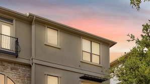 A multi-story building with a stone facade, a wooden door, and a balcony. - Townhome Located in the heart of Legacy Shops (Plano)