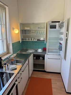 Et kompakt køkken med indbygget mikrobølgeovn, vask og et lille køleskab.