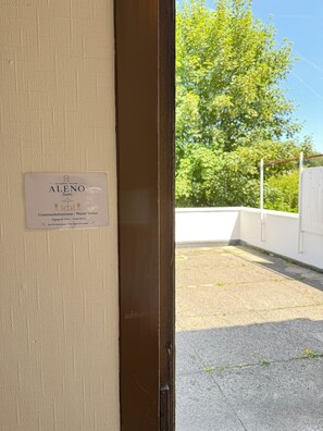 A door with a sign indicating 'ALENO Suites' and 'Gemeinschaftsterrasse / Shared Terrace' with guest access. - ALENO Suites near St. Gallen with 2 bedrooms and a parking space (Wittenbach)