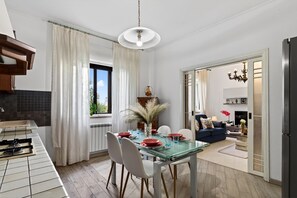 Una cucina moderna con zona pranzo, un soggiorno con divano e TV, e vista sull'esterno.