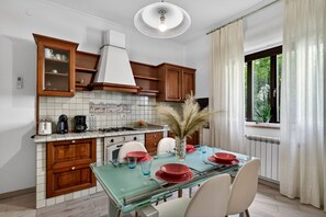 Una cucina moderna con mobili in legno, un tavolo in vetro e vista sul verde.