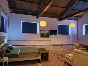 Un dormitorio con cama, una mesita, un sofá y una lámpara colgante.
