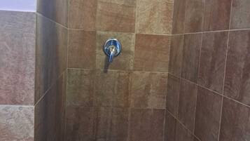 Une zone de douche carrelée avec un pommeau de douche amovible.