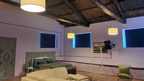 Una habitación con cama, sofá, sillón e iluminación colgante.