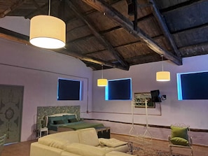 A room with a bed, a sofa, a chair, and pendant lights. - The Open Space Barn (Calabria)
