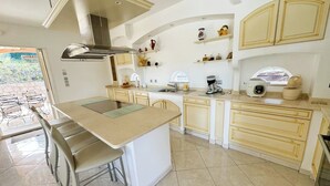 Una cocina moderna con una isla central, taburetes de bar, horno empotrado y cafetera.