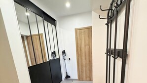 Un pasillo con un banco, perchero, puerta de madera y espejo.