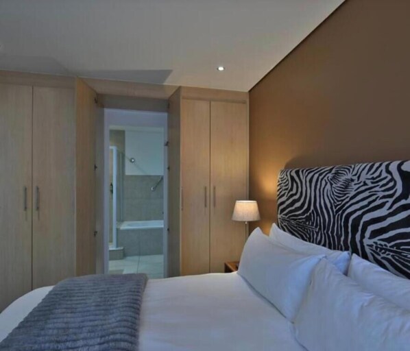 Ein Hotelzimmer mit einem Bett, einem Zebra-Muster-Kopfteil, einem Nachttisch mit einer Lampe und einem Kleiderschrank.