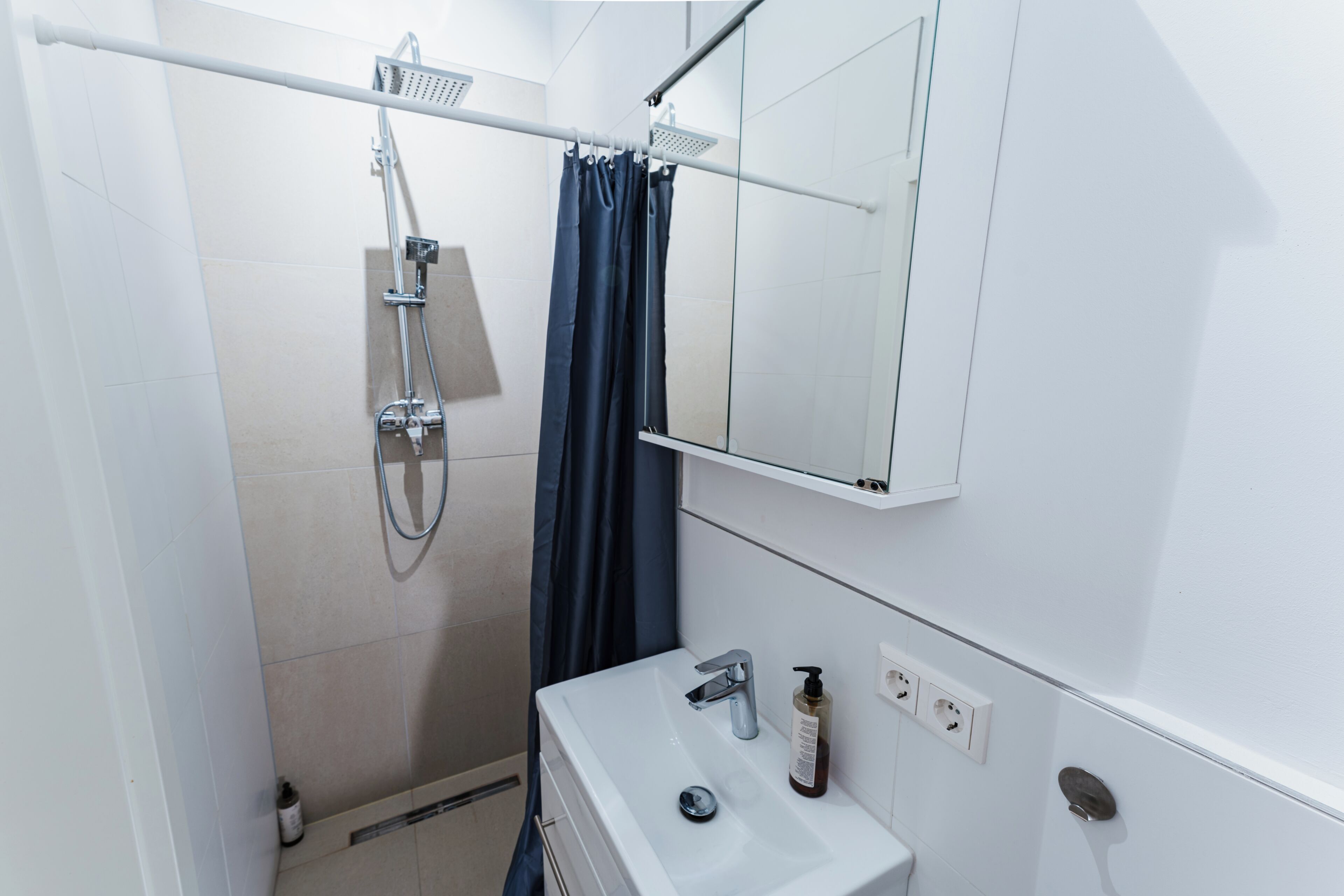 Une salle de bain équipée d’une douche, d’un lavabo, d’un miroir et d’un porte-serviettes.