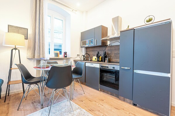 A compact kitchen with a dining area, modern appliances, and a view of the street.