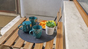 A wooden table with two teal mugs, a white mug with a plant, and a bowl of fruit. - SouthPark Luxe - Free Underground Parking (Sofia)