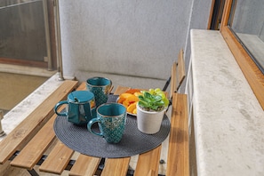 Ein Holztisch mit zwei türkisfarbenen Tassen, einer weißen Tasse mit einer Pflanze und einer Obstschale.