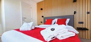 A hotel room with a bed, red and white bedding, a wooden panel wall, and a white wardrobe. - Le Verger - 6BR Gîte within Durbuy House Estate (Durbuy)