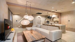 Un salon moderne avec un canapé d’angle, une table basse en bois et des lanternes en papier suspendues.