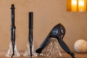Three hair styling tools on a wooden surface with a textured wall and a round object in the background. - JAPAVISTA Morino-to (TENGACHAYA, NISHINARI WARD)