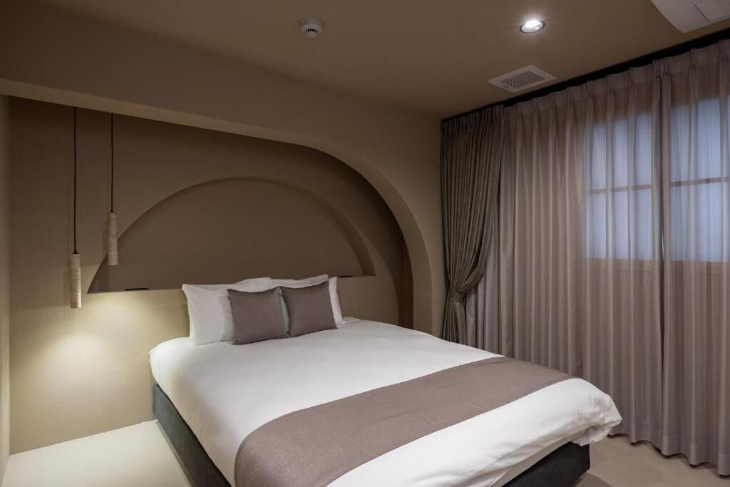 A modern bedroom with a large bed, a curved wall, and a window with curtains.