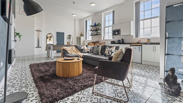 Een moderne woonkamer met een bank, salontafel en een decoratief vloerkleed.