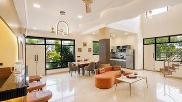 A spacious living area with a dining table, sofa, and kitchen in the background.