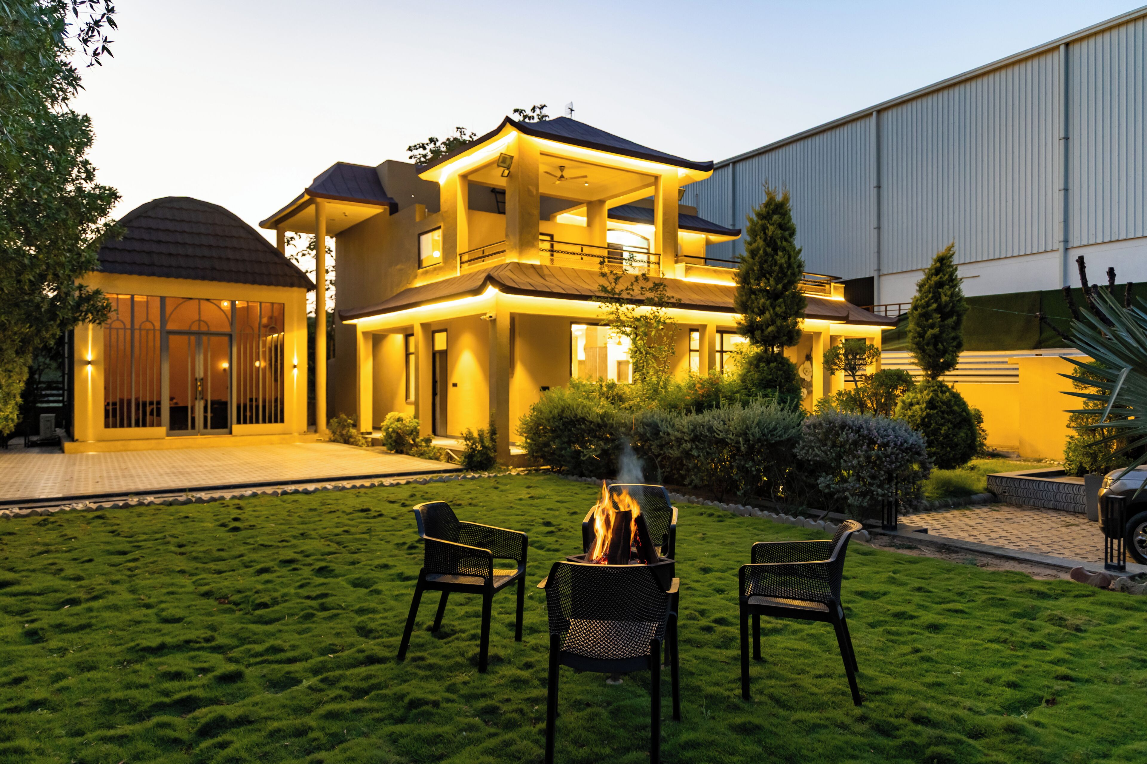 A two-story house with a fire pit in the yard, outdoor seating, and a large garage.