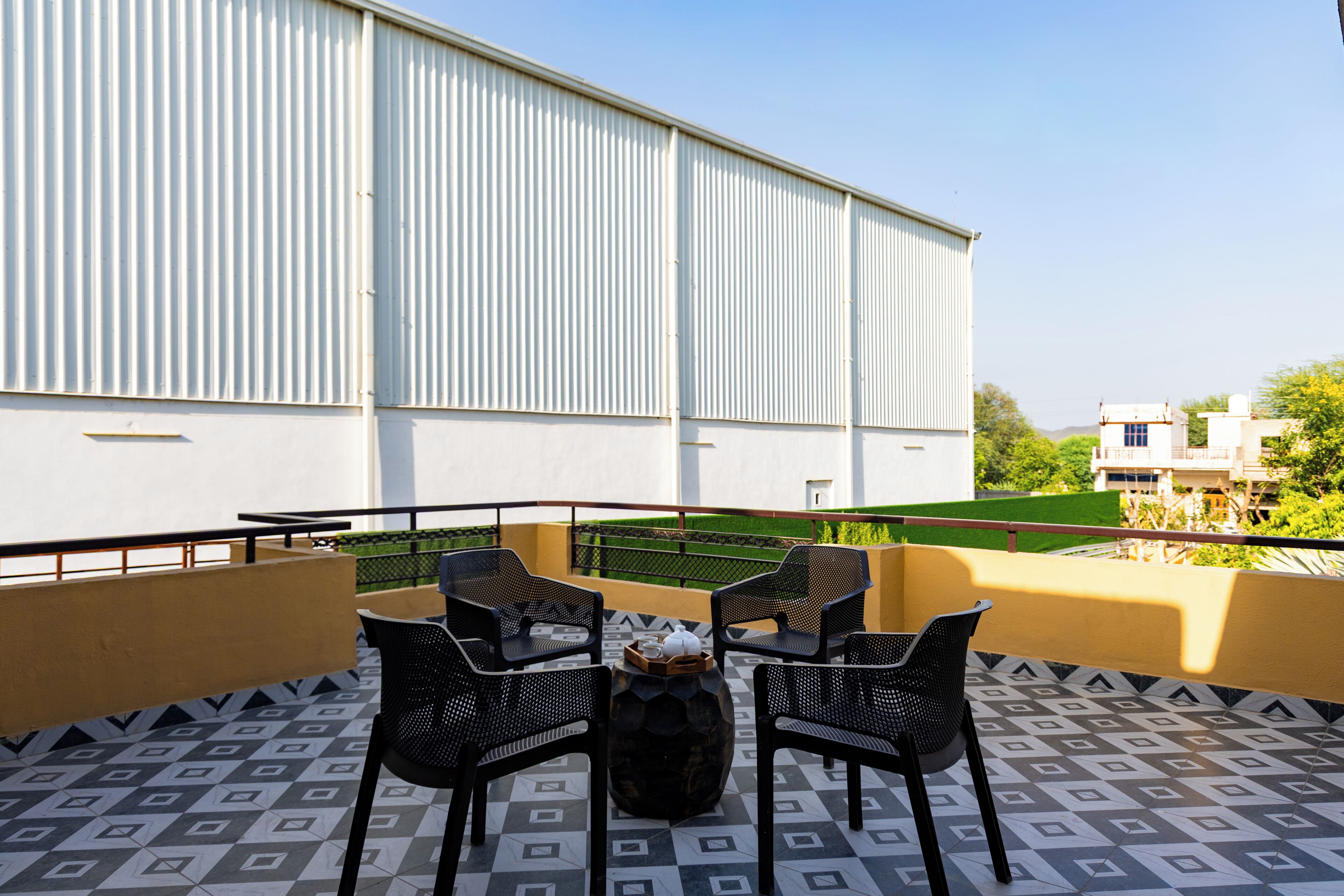 Una terraza con cuatro sillas, una mesa y un jarrón decorativo.