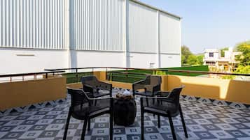 Una terraza con cuatro sillas, una mesa y un jarrón decorativo.