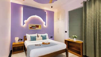Un dormitorio con cama, mesitas de noche, una mesita con un jarrón y un armario, además de un ventilador de techo.