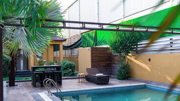 Uma piscina ao ar livre com área de estar, escorregador e pérgula.