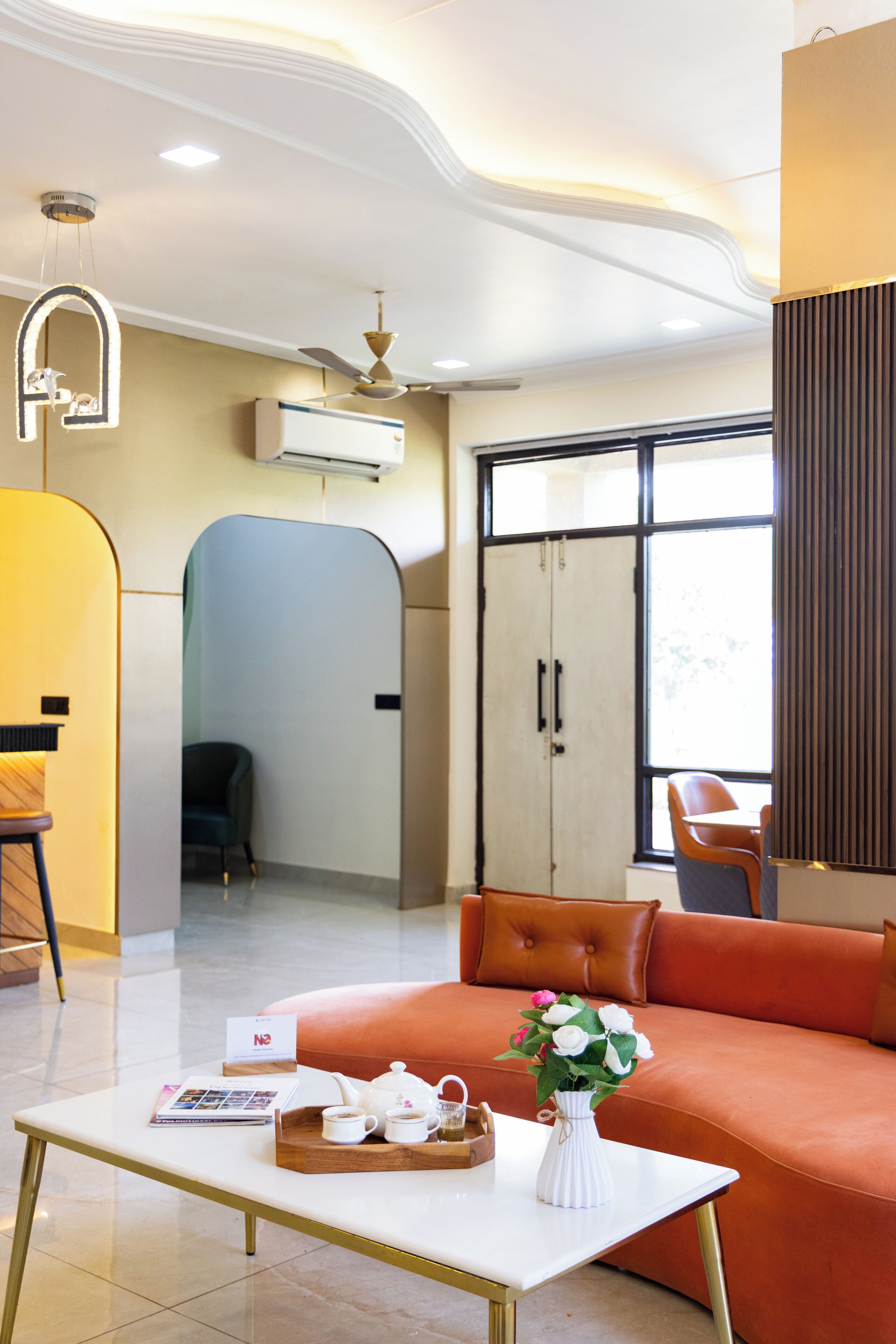 Una sala de estar moderna con un sofá, una mesita de centro con una bandeja, un florero y vistas al exterior a través de un gran ventanal.