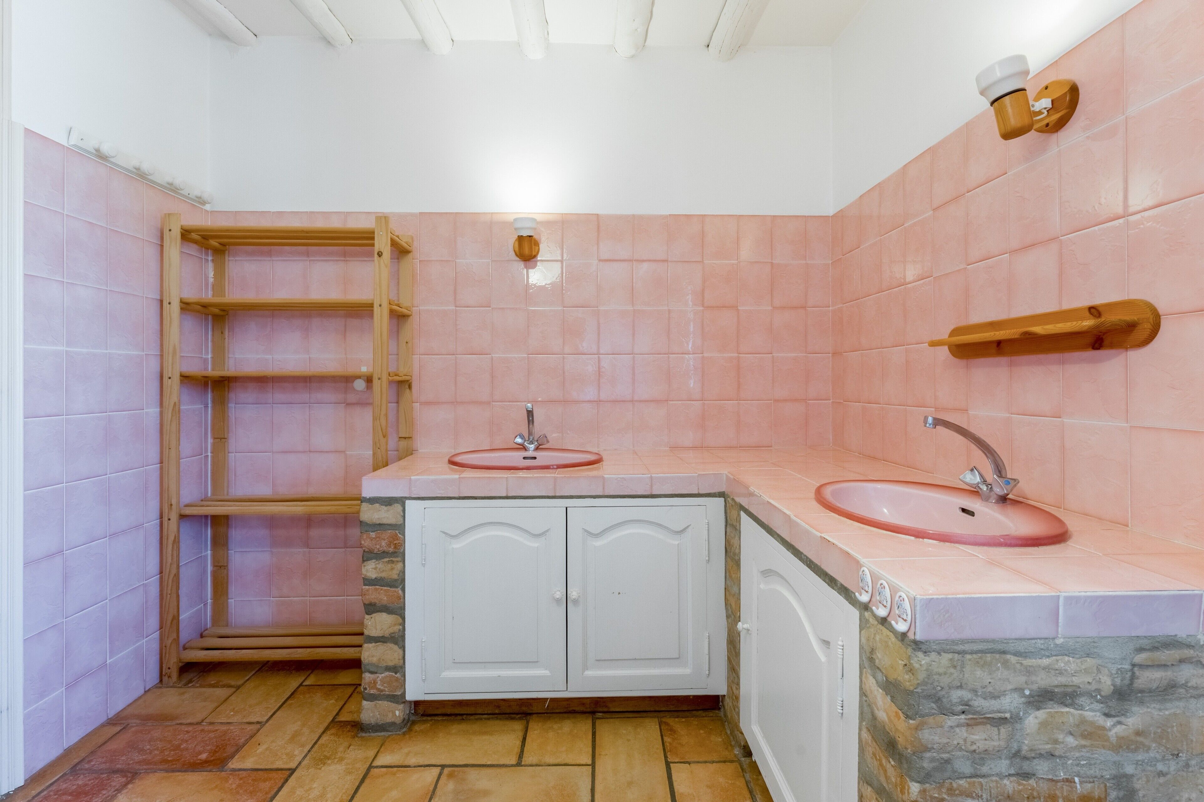 Une salle de bain avec deux lavabos, des étagères en bois et un mur d’accent en pierre.