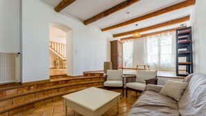 A living room with a sofa, chairs, a coffee table, a staircase, and a window with curtains. - Holiday Home "Mas des Amandiers" with Private Pool, Terrace, and Wi-Fi (Jonquières)