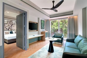 Une chambre d’hôtel moderne dotée d’un balcon, d’un canapé, d’une table basse et d’un téléviseur fixé au mur.