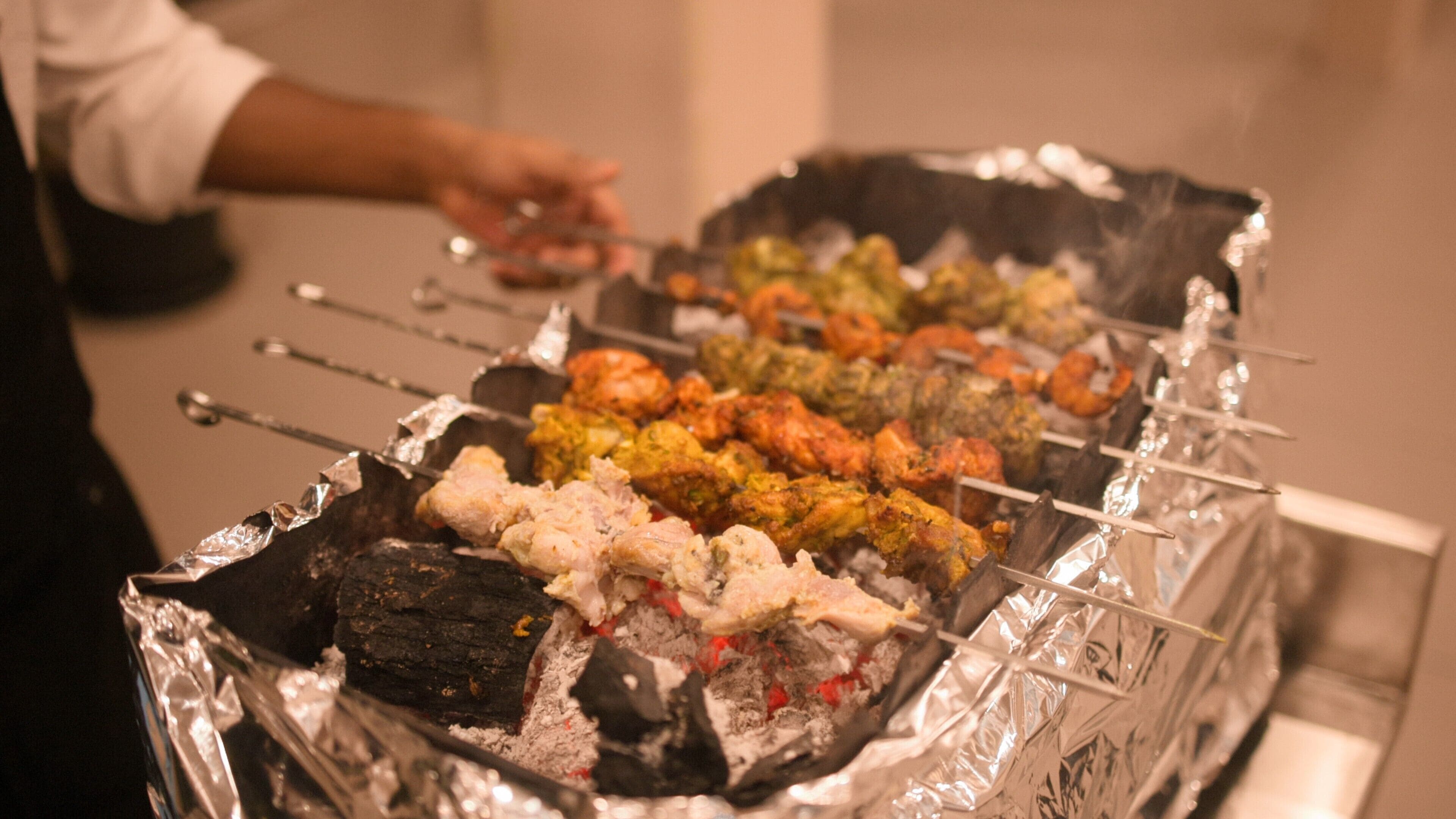 A grill with various skewers of food, including meats and vegetables, being cooked.