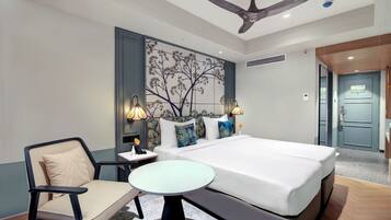 A hotel room with a bed, bedside table, chair, and a ceiling fan.