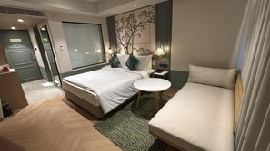 Een hotelkamer met een bed, een bank, een klein rond tafeltje en een muur met een bosreliëf.