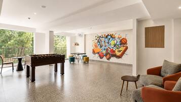 Una habitación amplia con mesa de fútbol de mesa, mesa de ping pong y un mural colorido en la pared.