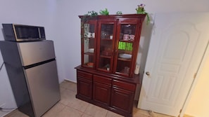 Uma cozinha com geladeira, micro-ondas e armário de madeira com portas de vidro.