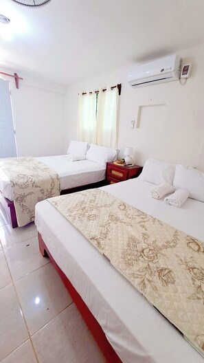 A hotel room with two beds, a red nightstand, a lamp, and an air conditioning unit. - Just 5 minutes from the Los Patos River! 3-bedroom house with terraces and a kitchen (Los Patos)
