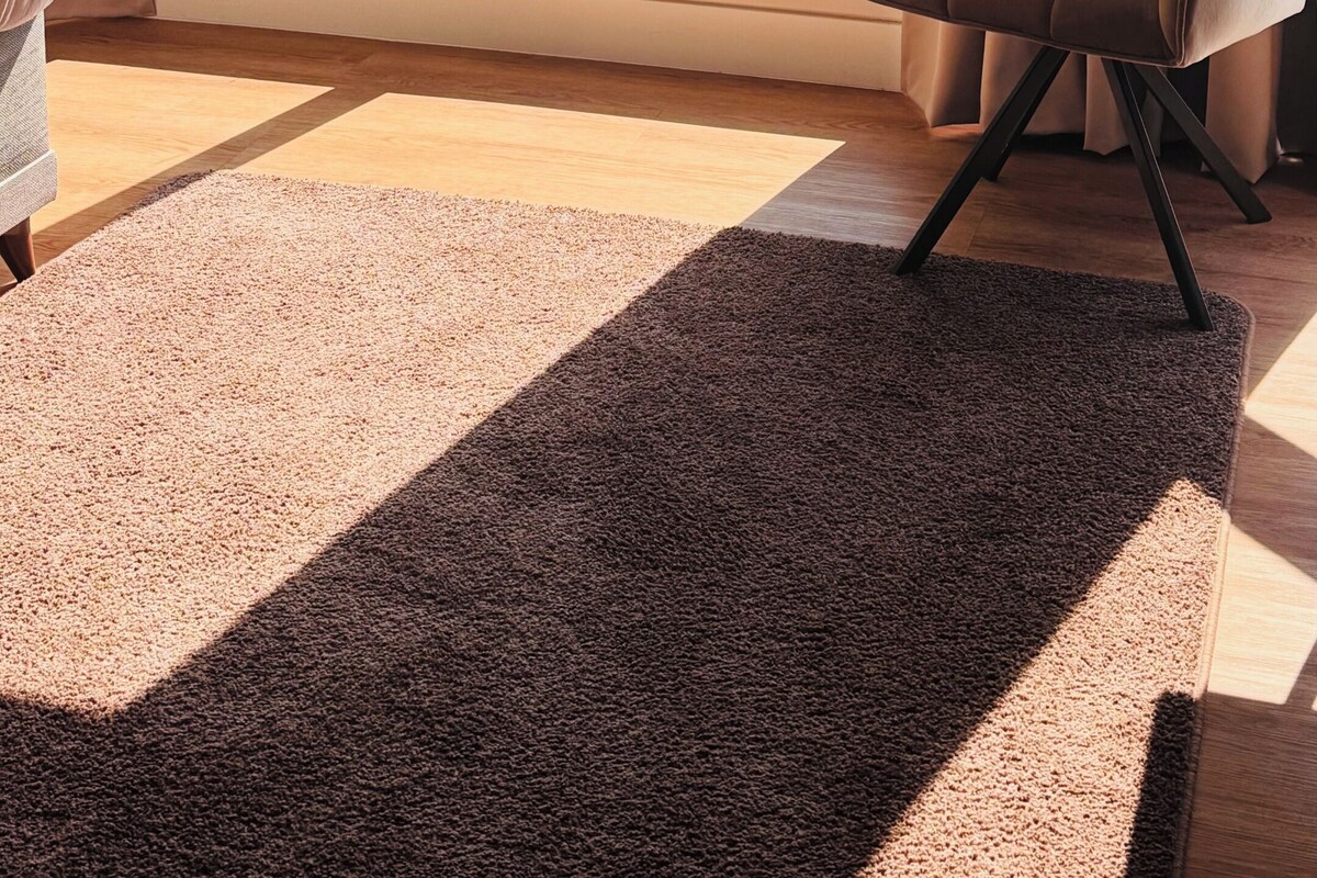 Quarto com uma janela grande, uma cadeira, um tapete e uma cama.