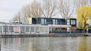 Una propiedad frente al agua con un área de estar cubierta al aire libre, un edificio con balcón y vista al agua.
