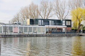 Um imóvel à beira-mar com área de estar coberta ao ar livre, um edifício com varanda e vista para a água.