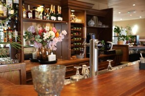 Un espace bar avec un assortiment de bouteilles, un distributeur de boissons en verre et un arrangement floral.