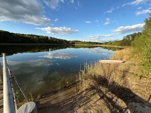 Ein ruhiger See mit einer hölzernen Anlegestelle, umgeben von Bäumen und Vegetation.