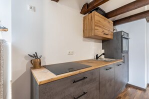 A compact kitchen with a wooden countertop, grey cabinets, and a built-in oven.