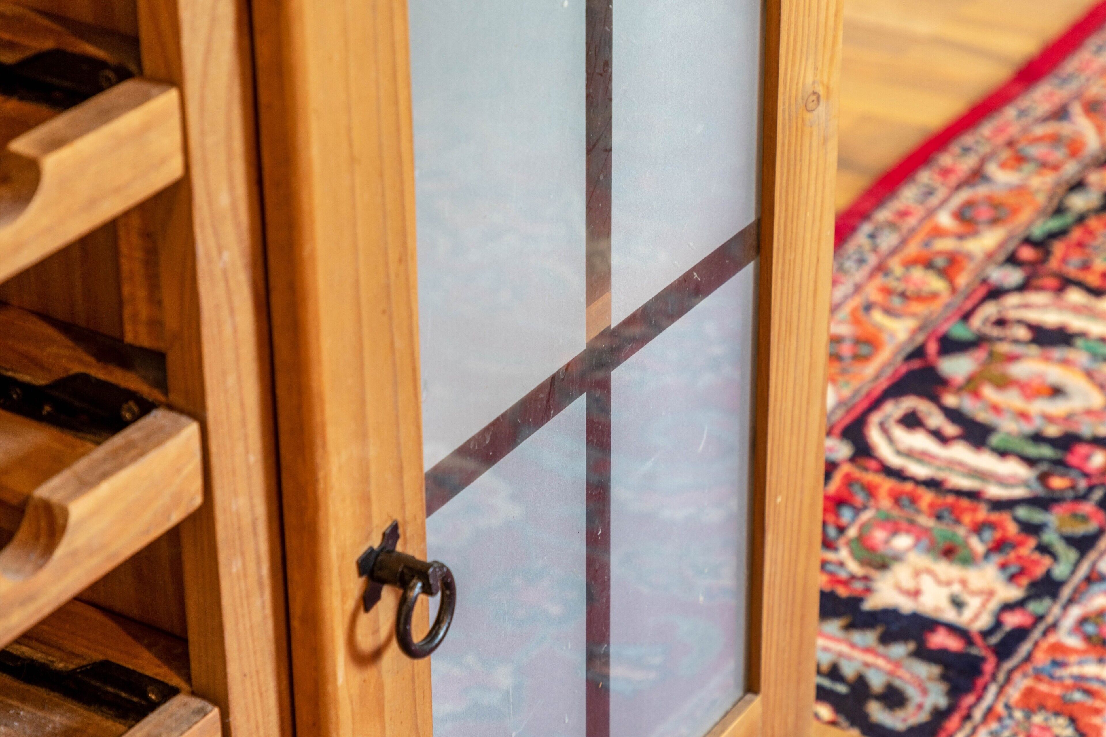 Une porte en bois avec une poignée en métal, un panneau de verre et un tapis à motifs.