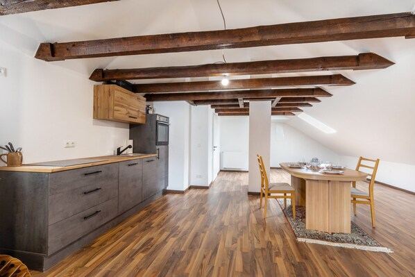 Una cocina moderna con vigas de madera, una mesa de comedor con sillas y vistas al área de estar.
