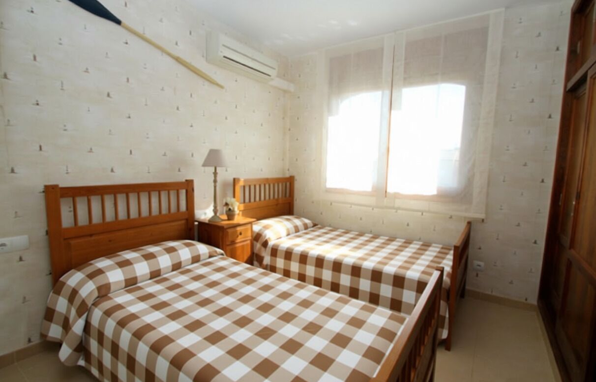 Une chambre avec deux lits, une table de chevet, une lampe et une fenêtre.