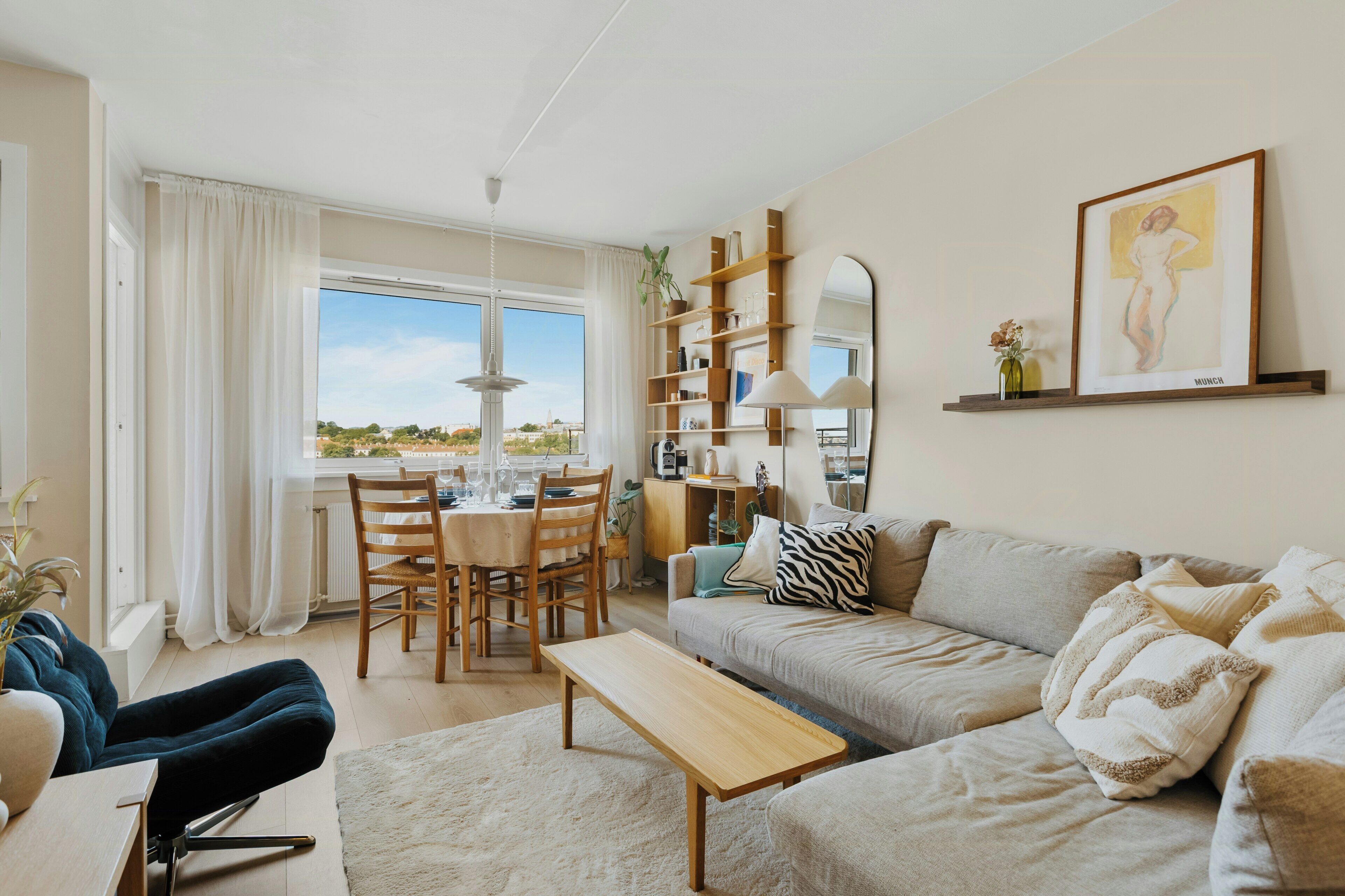 En moderne stue med sofa, sofabord, spisebord med stole og bogreol.