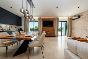 A modern dining area with a long table, chairs, and a chessboard. - Villa Krišto Zadarvillas (Privlaka)